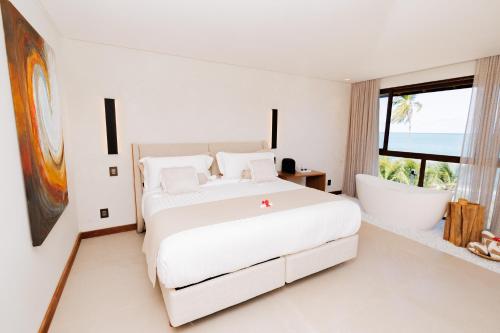 a bedroom with a large bed and a bath tub at Almareia Boutique Hotel in Praia dos Carneiros