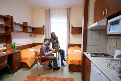 a woman standing in a room with a man in a hotel room at Study K & M Hotel in Debrecen