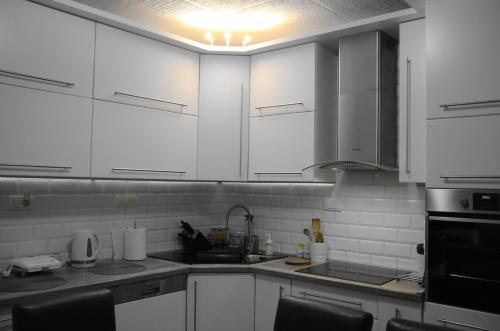 a white kitchen with white cabinets and black appliances at Cerak lux in Bele Vode