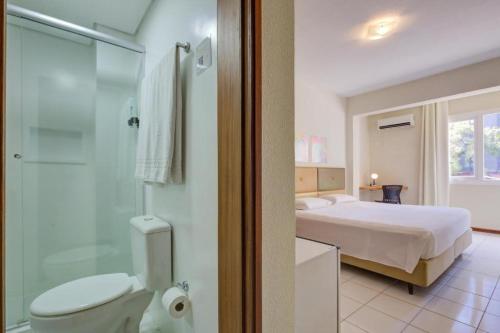 a bathroom with a bedroom with a bed and a shower at GoldMen Business Joinville in Joinville