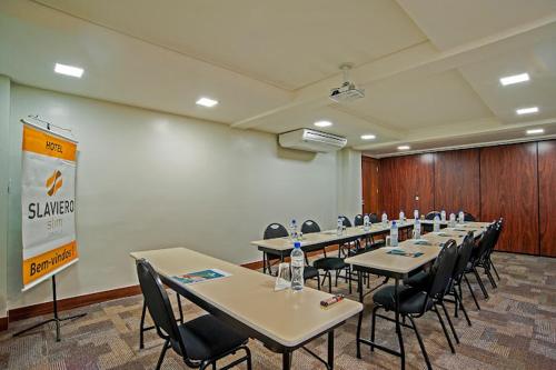 a conference room with tables and chairs and a screen at GoldMen Business Joinville in Joinville