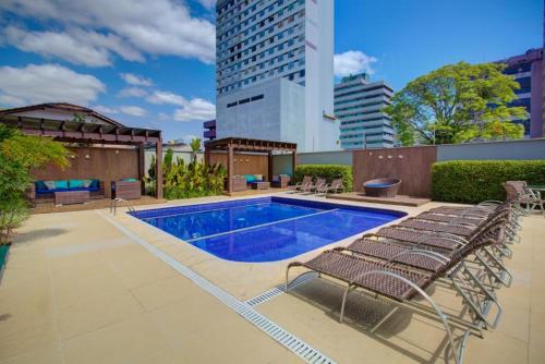 a swimming pool with chairs next to a building at GoldMen Business Joinville in Joinville