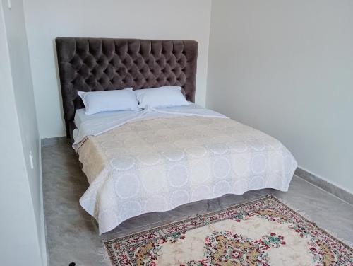 a bed with a padded headboard and a rug at Royal Stay in Kira