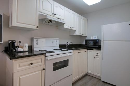 a kitchen with white cabinets and a white refrigerator at Travelodge by Wyndham Kamloops Mountview in Kamloops
