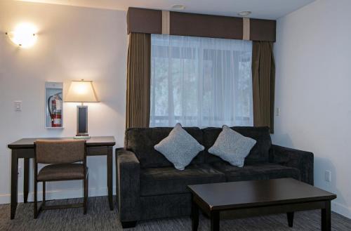 a living room with a couch and a table at Travelodge by Wyndham Kamloops Mountview in Kamloops