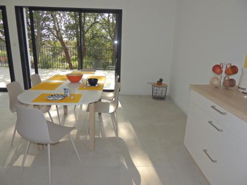 eine Küche mit einem gelben Tisch und weißen Stühlen in der Unterkunft Villa neuve à 900 m de la plage in Santa-Lucia-di-Moriani