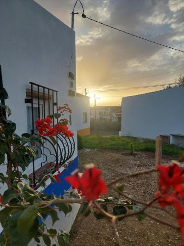 a fence with red flowers in front of a building at Casa da Pedra in Cabeça de Carneiro