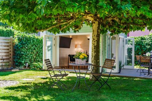 a patio with a table and chairs under a tree at Bregenzer Traum am Bodensee inkl Fahrräder in Bregenz