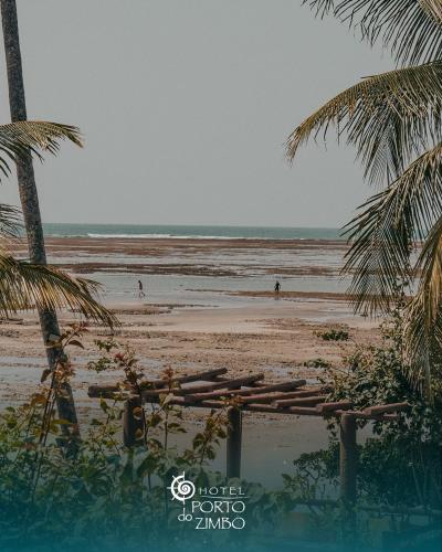a beach with palm trees and people on the beach at Hotel Porto do Zimbo in Morro de São Paulo