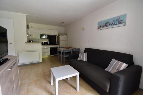 a living room with a black couch and a kitchen at Escapade Provençale - T2 avec cuisine et terrase privée in Digne-les-Bains
