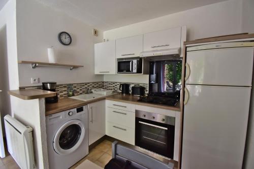 une cuisine avec des armoires blanches et une laveuse et une sécheuse dans l'établissement Escapade Provençale - T2 avec cuisine et terrase privée, à Digne-Les-Bains