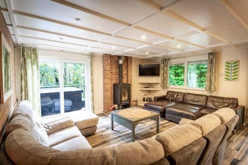 a living room with a couch and a fireplace at Weaver, woodland lodge with hot tub for 12 in Oakamoor