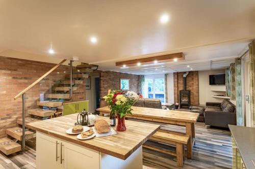 a kitchen and living room with a table and a couch at Weaver, woodland lodge with hot tub for 12 in Oakamoor