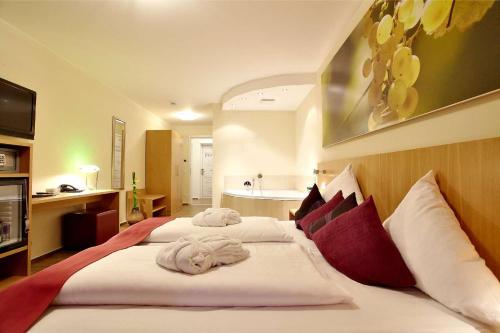 una camera da letto con un grande letto con cuscini rossi e bianchi di Christiana's Wein & Art Hotel a Bernkastel-Kues