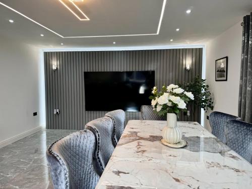 a dining room with a table with chairs and a television at Lux 7 Bedroom residence in Waterlooville