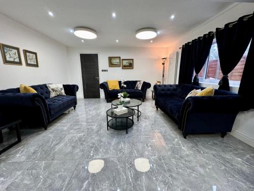 a living room with blue couches and a table at Lux 7 Bedroom residence in Waterlooville