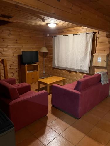a living room with purple couches and a table and a screen at Chalé 40 - Penhas da Saúde in Penhas da Saúde