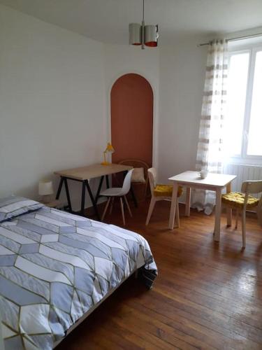 une chambre avec un lit, une table et des chaises dans l'établissement Superbe appartement sur cour arborée, à Dijon