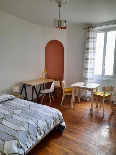 une chambre avec un lit, une table et des chaises dans l'établissement Superbe appartement sur cour arborée, à Dijon