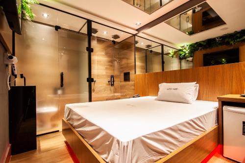a bedroom with a large bed and a shower at Motel Jardim Secreto in Santo André