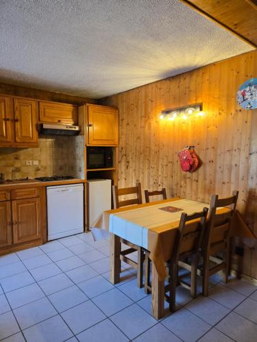 une cuisine avec une table, des chaises et un réfrigérateur dans l'établissement Chaleureux refuge thermal, à Saint-Gervais-les-Bains