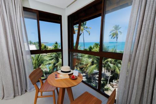 a room with a table and chairs with a view of the ocean at Almareia Boutique Hotel in Praia dos Carneiros