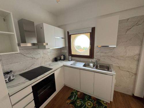 a kitchen with white cabinets and a sink and a window at 085 luxury apartment in Montesilvano