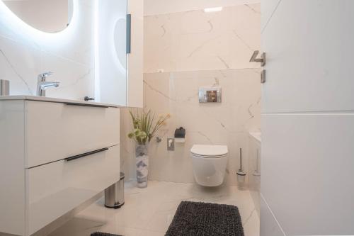 a white bathroom with a toilet and a sink at KARINA APARTMAN in Dunajská Streda