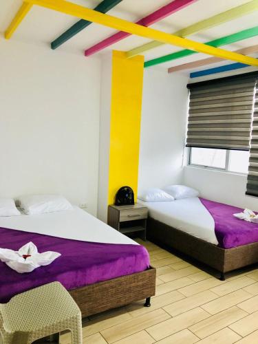 two beds in a room with colorful walls at Hotel Café Color in Armenia