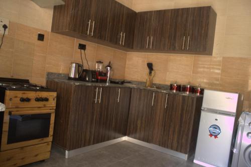 a kitchen with wooden cabinets and a white refrigerator at The Vistana 4Bedroom Pearly Gate Estate Ikota VGC Lekki in Igboshere