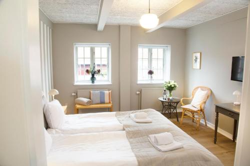 a bedroom with two beds and a desk and two windows at HotelVFjorden in Lemvig