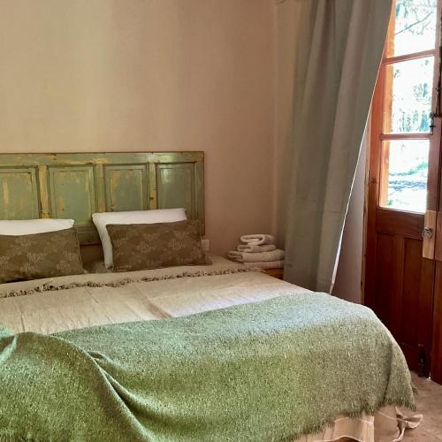 a bedroom with a bed with a green headboard and a window at Cuenca del Bosque in Tandil