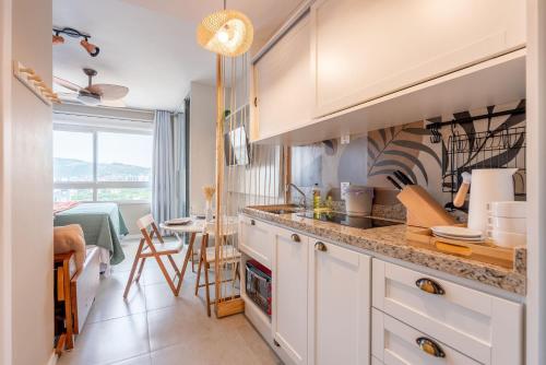a kitchen with white cabinets and a table in a room at Connect by LikeHome in Porto Alegre