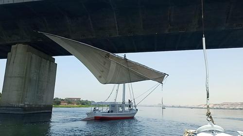 a boat in the water under a bridge at Nuba Tod Sailling boat in Aswan