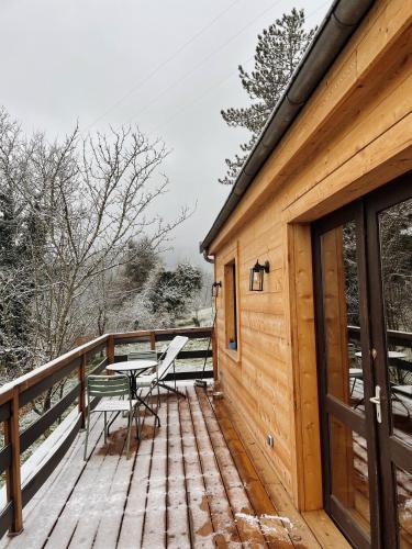 une terrasse en bois avec une table et des chaises dessus dans l'établissement Little Loue, au bord de la rivière, à Chenecey-Buillon