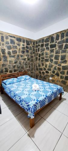 een bed in een kamer met een stenen muur bij Chalé do corisco in Paraty