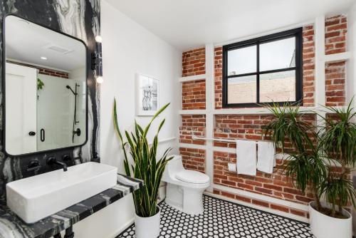 a bathroom with a white sink and a brick wall at The Brick Boutique Hotel in Oceanside