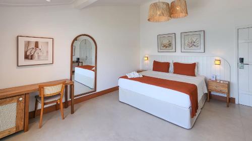 a bedroom with a bed and a desk and a mirror at Byblos Pousada in Búzios