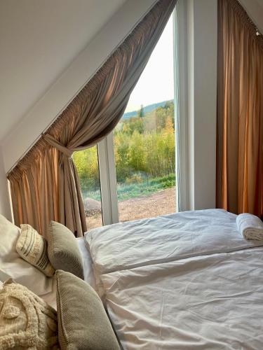 a bed in a bedroom with a large window at Domki Granero w Górach Sowich in Grzmiąca