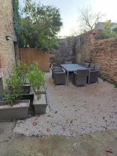 a patio with a table and chairs and plants at Le retour aux sources in Nolay