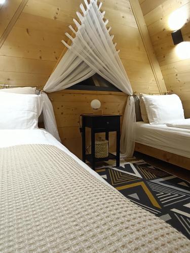 a bedroom with two beds and a table in a room at Stone Chalets - LUNA in Jajce