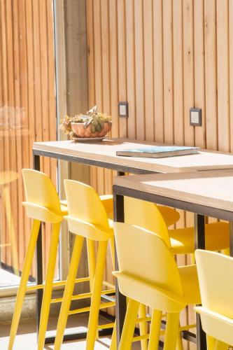 a table with yellow chairs and a bowl of fruit at Apart Hotel Jardín in El Calafate