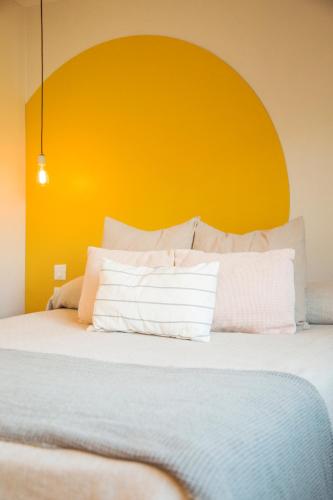 a bed with an orange headboard and white pillows at Apart Hotel Jardín in El Calafate