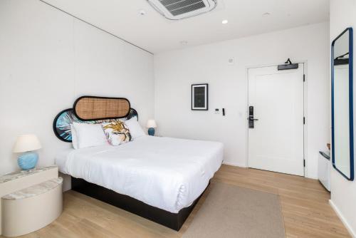 a white bedroom with a white bed and a door at The Brick Boutique Hotel in Oceanside
