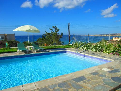 a swimming pool with two chairs and an umbrella at Aura Holiday Villas in Paphos