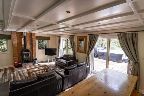 a living room with leather furniture and a fireplace at Farley, woodland lodge with hot tub for 8 in Oakamoor