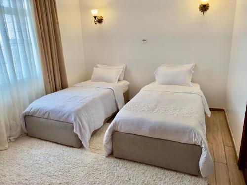 a bedroom with two beds and a window at Best homes apartments near JKIA in Nairobi