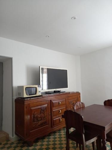 - une télévision au-dessus d'une commode en bois avec une table dans l'établissement Appartement St Jacques, à Saint-Gervais-sur-Mare