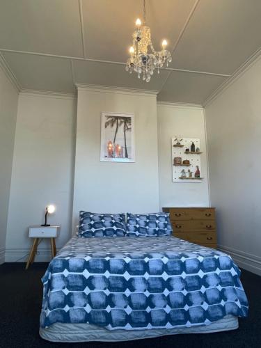 但尼丁Low Cost Accommodation的一间卧室配有一张大蓝色的床和吊灯