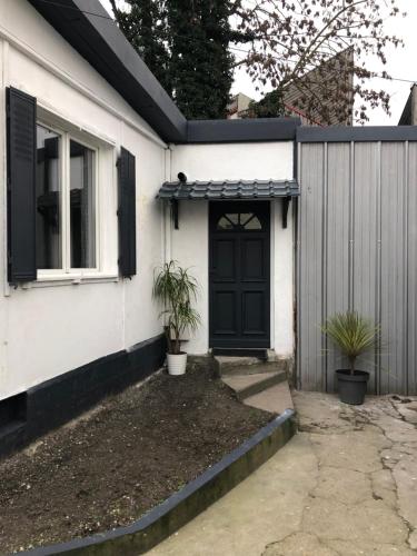 une maison blanche avec une porte noire et une clôture dans l'établissement Chalet, au Blanc-Mesnil